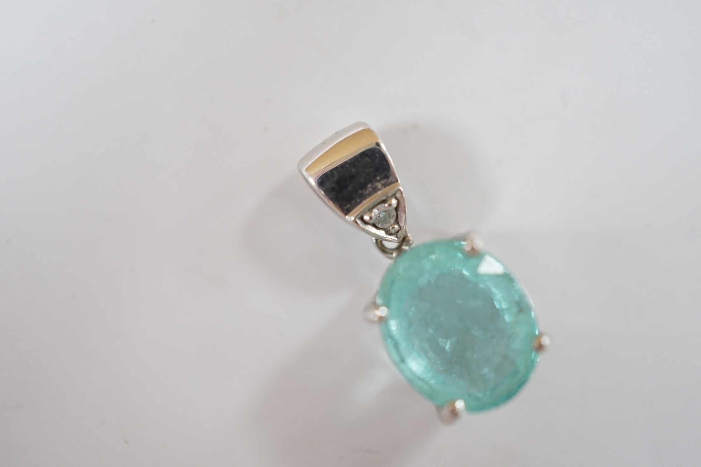 An 18ct white gold and single stone oval cut paraiba tourmaline pendant, with single stone diamond set bale, overall 19mm, gross weight 3.7 grams.